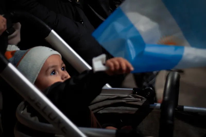 Bebé en un cochecito mirando una bandera argentina