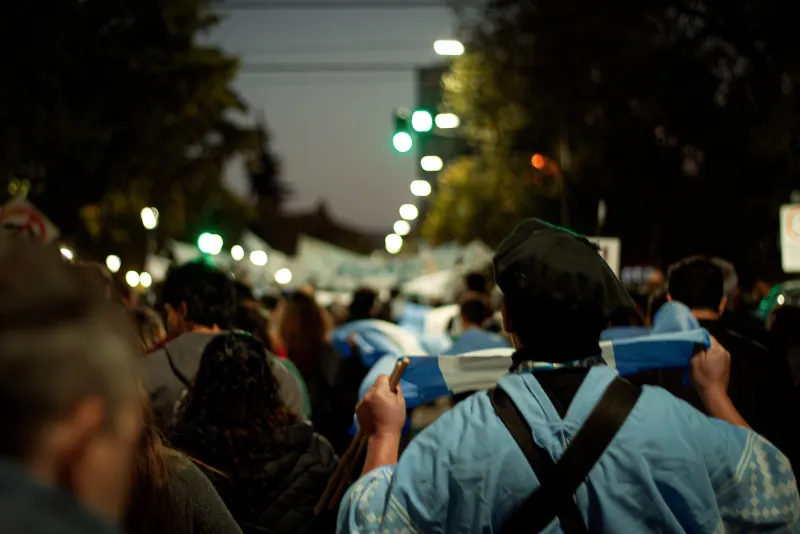 Columna de manifestantes de noche bajo las luces de la calle