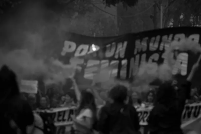 Bandera «Por un mundo feminista» entre el humo