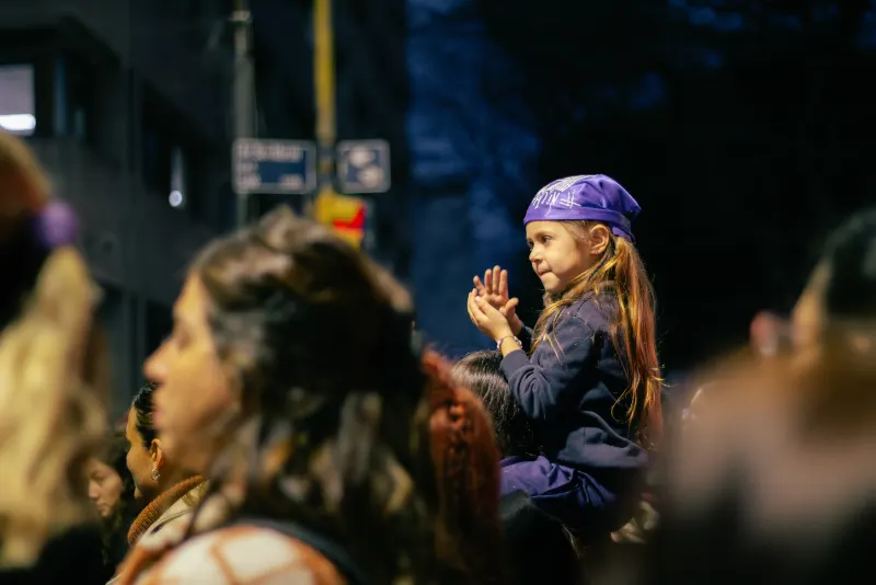 Niña con pañuelo violeta aplaudiendo en la marcha