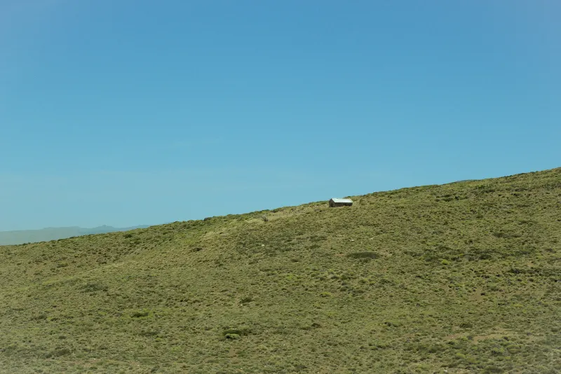 Ladera verde con una construcción a lo lejos
